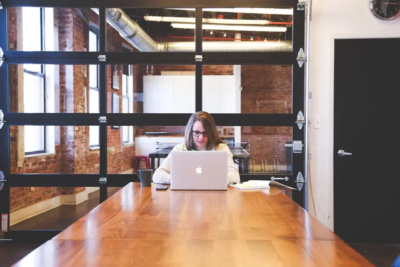 Person working on a laptop at a long table in a loft office