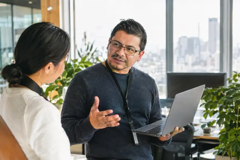 Engineer with a laptop talking with a colleague in an office